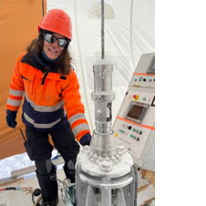 A person in orange jacket and helmet standing next to a machine
AI-generated content may be incorrect.